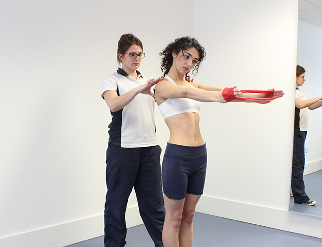 Experienced physiotherapist instructs patient how to carry out exercise.