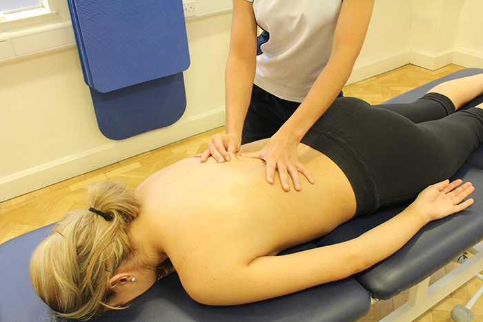 Rolling massage technique on lower back in Manchester clinic