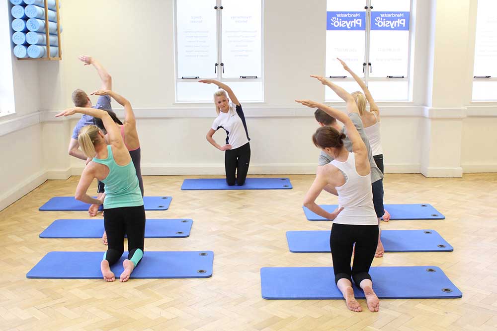 Group pilates session warm up on mats. Group pilates session warm up on mats.