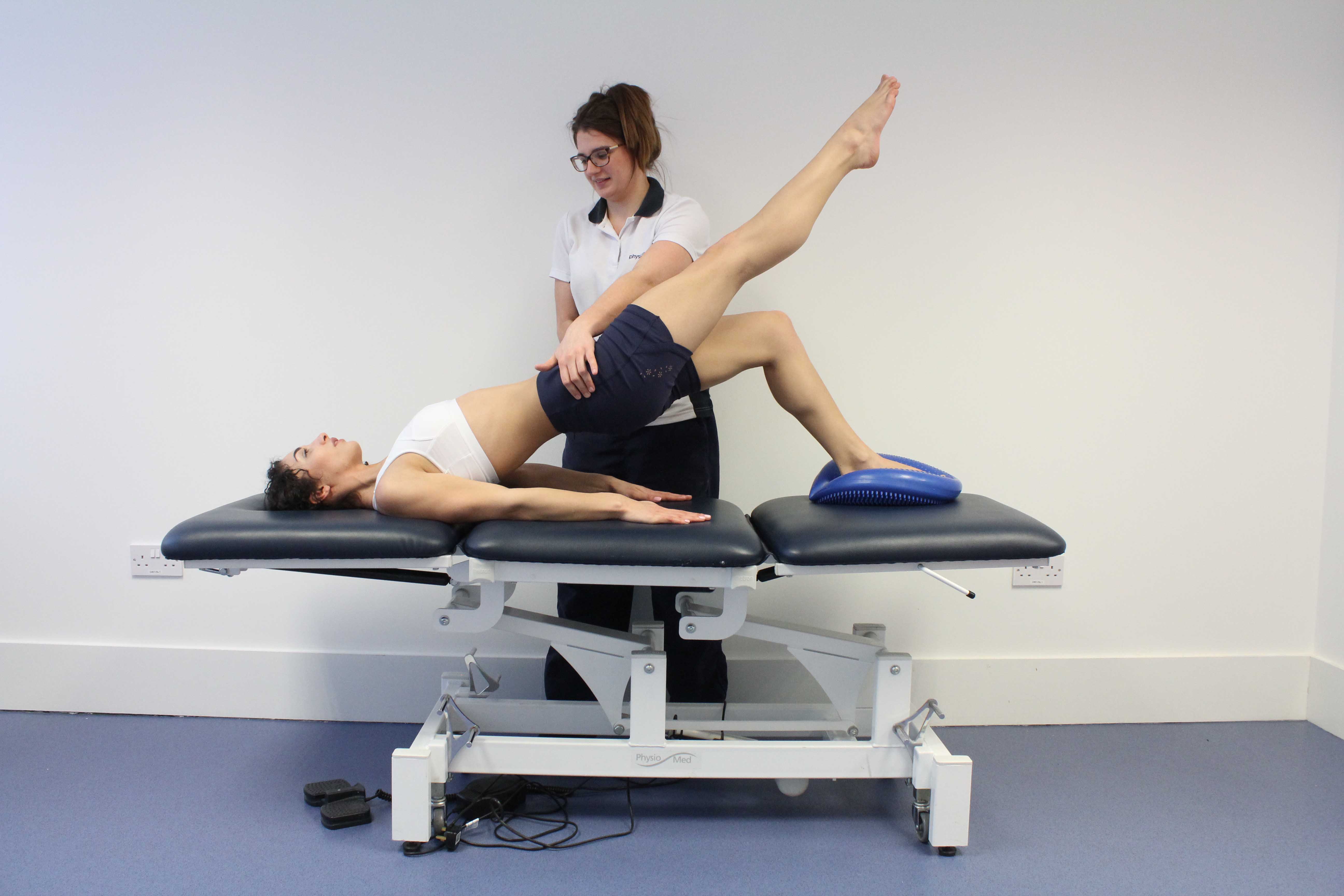 Leg strengthening exercises using squats and a gym ball with hand weights, under supervision of specialist MSK physiotherapist