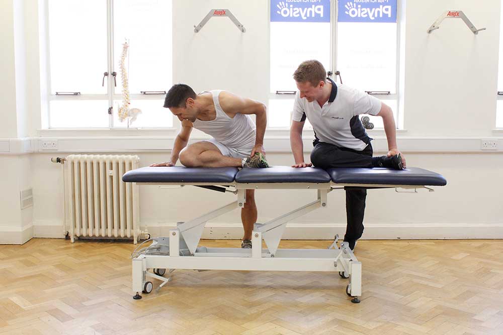 Specialist physiotherapist guiding client through hip and knee stretches for runners