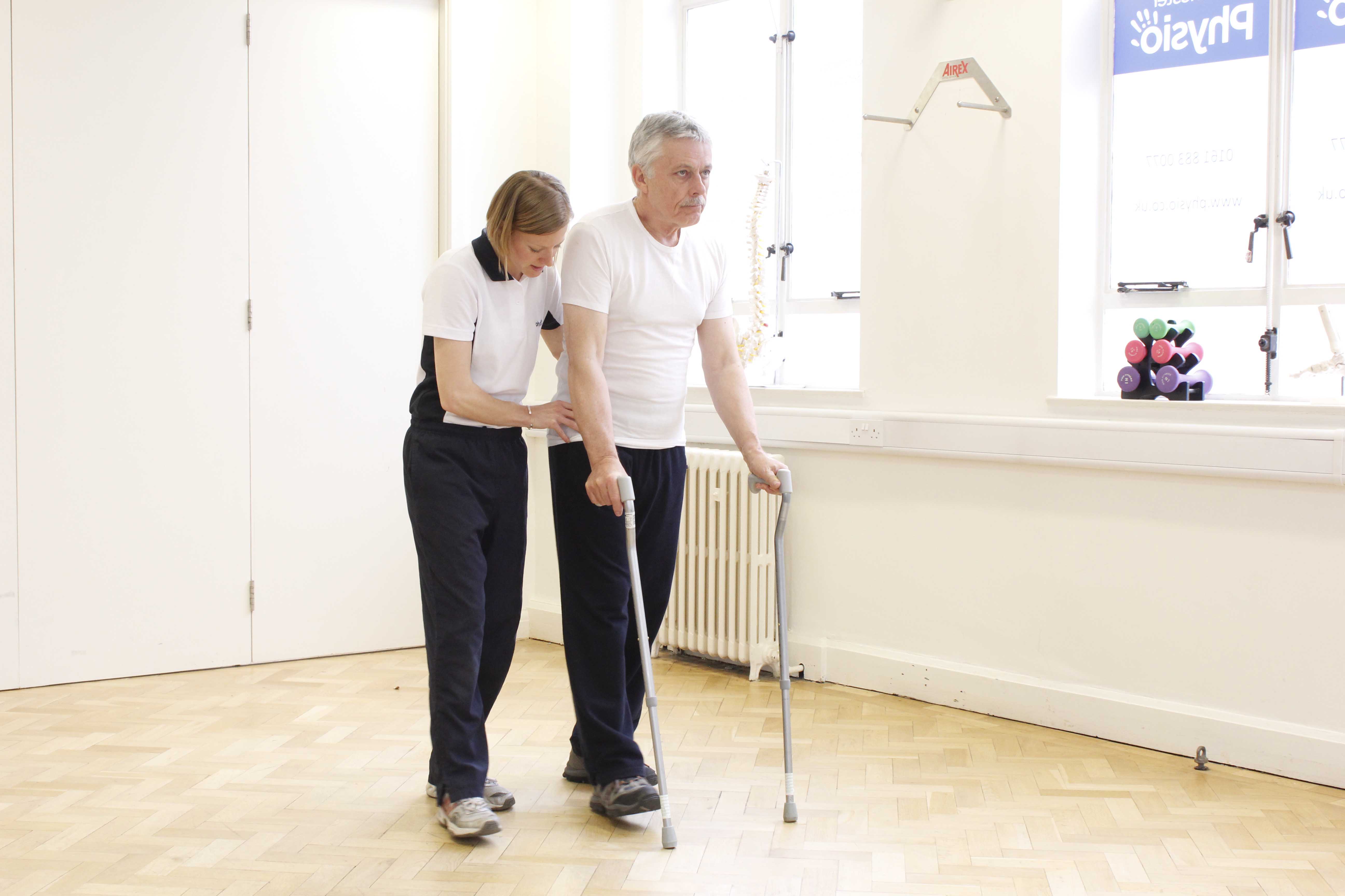 Neurological physiotherapist supervising mobility exercises using a pair of walking sticks