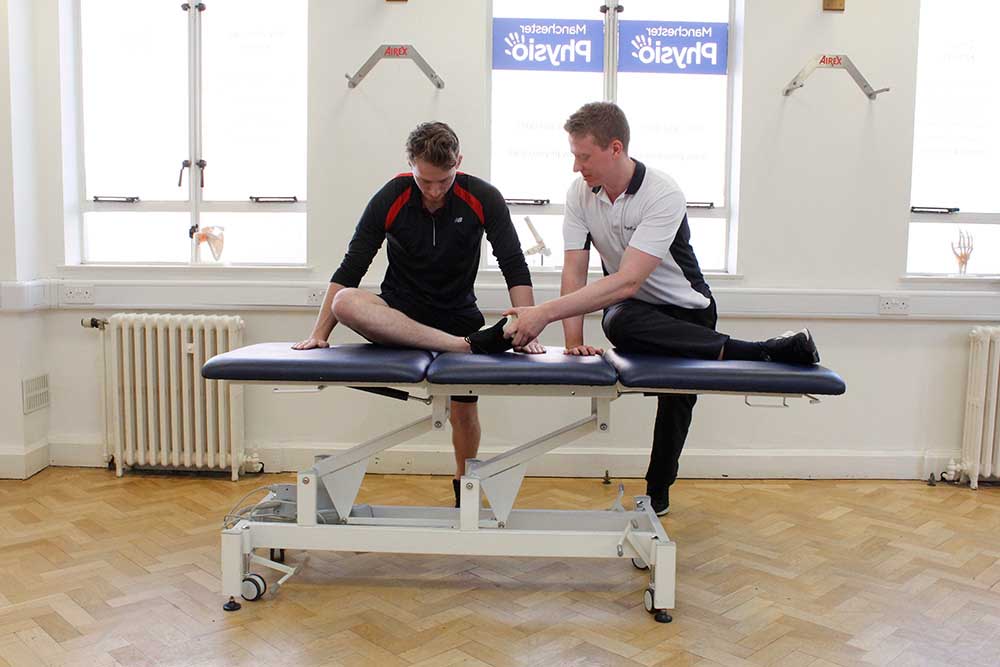 Specialist musculoskeletal Physiotherapist supervising hip and knee stretches for sports rehabilitation Specialist musculoskeletal Physiotherapist supervising hip and knee stretches for sports rehabilitation